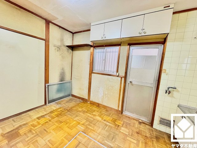 キッチン横には勝手口があり、換気やゴミ出しなどに便利です。上部には吊戸棚も設置されており、スッキリとした空間が保てます。