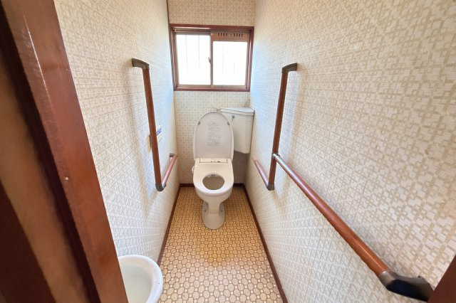 奥行きのあるゆったりとしたトイレ空間。両側に手すりが設置されており、立ち座りの動作をしっかりサポートします。窓付きのため自然換気ができ、明るさも感じられるのが魅力。シンプルで使いやすい設備構成です。