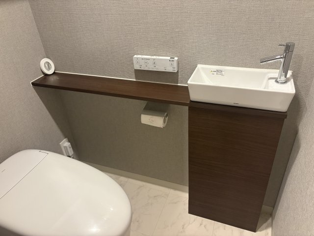 ※　CGで家具等を削除(設置)したイメージです。清潔感あふれる独立型のトイレ空間。快適な温水洗浄便座を標準装備しており、ペーパー類や掃除用具をスマートに収納できる棚も備えています。手洗器も標準仕様。