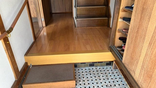 手すり付きの上がり框と木目調の靴箱を完備した玄関ホール