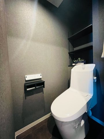 お手入れのしやすい温水洗浄便座付きトイレ。奥の壁面にはトイレットペーパー等の保管に便利な収納棚を備えています。