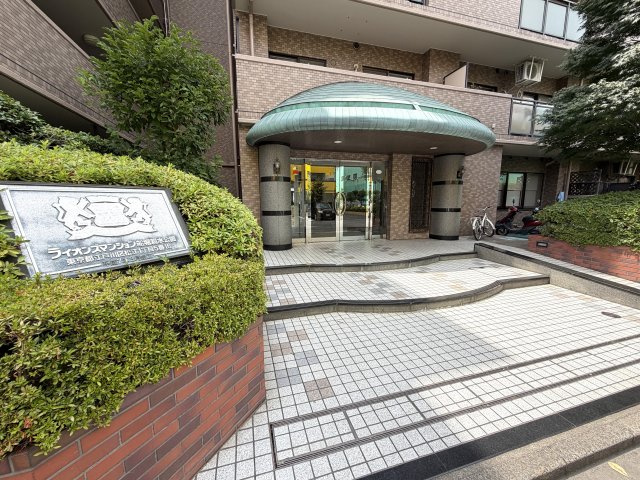 重厚な銘板と特徴的なキャノピー（庇）が目を引くエントランス。美しく整備された植栽と上品なタイル敷きのアプローチが、住まう方を誇り高くお迎えします。