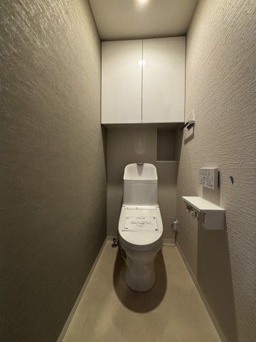 シックな色合いのトイレには、扉付きの収納もあります。