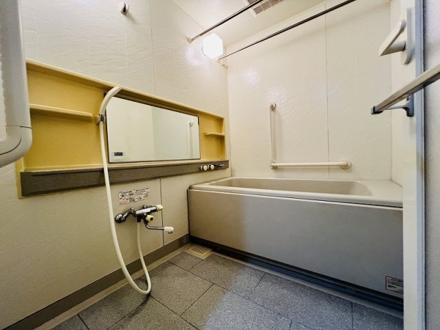 浴室乾燥機や手すり付きで快適なバスタイム。ワイドミラーや便利な棚も備えた清潔感のある浴室です。
