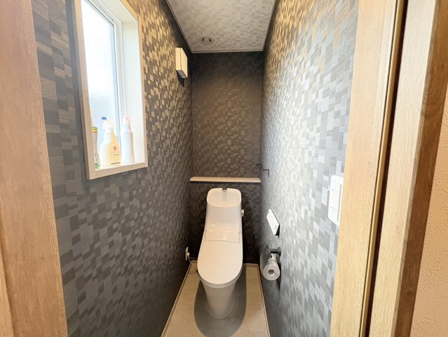 落ち着いたクロスがおしゃれなトイレ空間。清潔感を保ちやすいのが魅力です。温水洗浄便座付きで快適性も確保されており、カウンターも備わっているため小物の設置やディスプレイにも便利な使い勝手の良い空間です。