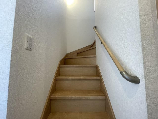 手すり付きで昇り降りしやすい階段スペース。窓から自然光が入り、昼間も明るく開放感を感じられます。木目調で統一された内装が住まい全体に温かみを演出。階段部分も圧迫感を感じにくい設計となっております。