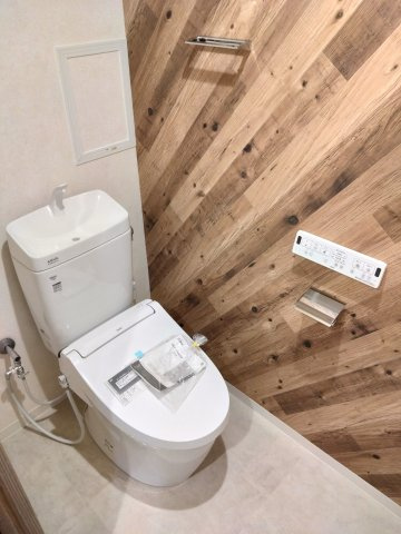 木目調のアクセントクロスが温もりを感じさせるトイレ空間。温水洗浄便座つきの洋式トイレは、手元で操作できる壁面リモコンで快適な使い心地です。