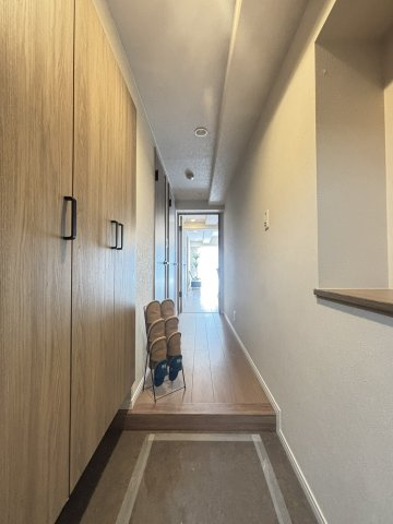 【玄関】室内から廊下方向を見渡した玄関エリアです。フロアタイル仕様の上がり框と木目調のシューズボックスが備わっています。