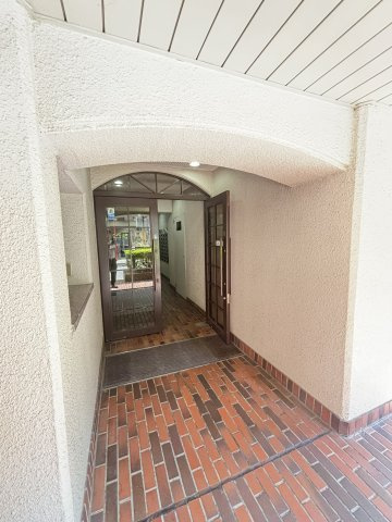 【エントランス】マンションの玄関口にあたるエントランス部分です。アーチ状の庇と格子状のガラスドアが設置されています。
