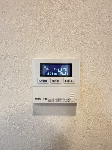 【給湯器リモコン】壁面に設置された給湯器のリモコンです。お湯の温度設定や沸き増しなどの操作が可能です。