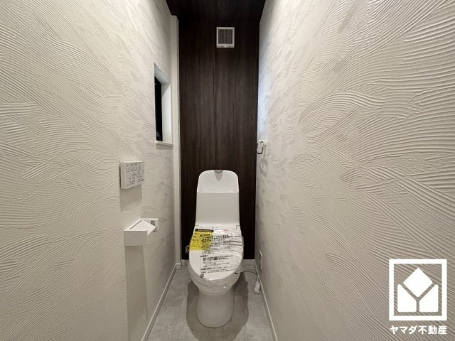 上品な壁紙と木目調のアクセントクロスが魅力的なトイレ空間。機能性とセンスが融合した、居心地の良いプライベートスペースです。