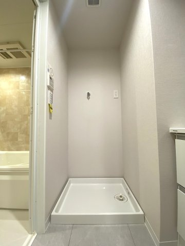 洗面室内に備え付けられた洗濯機置場です。周囲には洗剤や洗濯小物を置けるスペースがあり、毎日の洗濯作業を効率よく行える機能的な動線設計となっており非常に便利です。