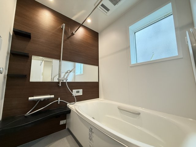 落ち着いた木目調パネルが印象的な浴室。ゆったりとした浴槽で一日の疲れをしっかり癒せます。窓付きで換気がしやすく、清潔感を保ちやすい仕様。シンプルながら機能性とデザイン性を兼ね備えた空間です。　