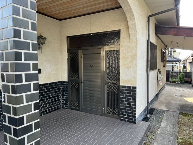 アーチ状のポーチと装飾格子付きの玄関ドアが、住まいの顔として風格を演出しています。ゆとりあるタイル貼りのポーチは雨の日でも出入りしやすく、来客時にも安心落ち着いた雰囲気を感じられるエントランスです。
