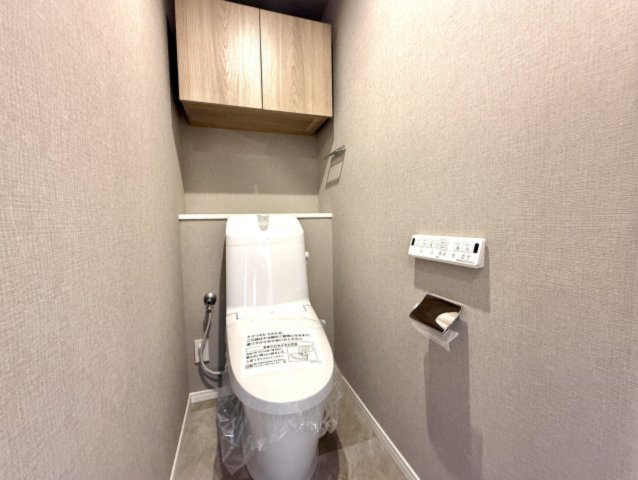トイレはシンプルに落ち着いたカラーのアクセントクロスを使用。戸棚もあるので、トイレットペーパーや掃除用具なども見せずにしっかり収納できます。