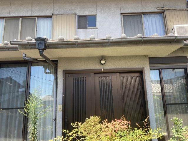 重厚感のある引き戸タイプの玄関が印象的な外観。左右には大きな開口部があり、昔ながらの住宅らしい落ち着いた佇まいです。植栽の緑が玄関まわりに彩りを添え、どこか懐かしさを感じさせる住まいの表情が魅力です。
