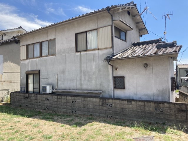 建物周辺には戸建住宅が立ち並び、昔ながらの住宅地らしい穏やかな街並みが広がります。建物の側面にも空間があり、隣接地との位置関係も現地で確認できます。青空や周囲の緑が映える、のどかな住環境が魅力です。