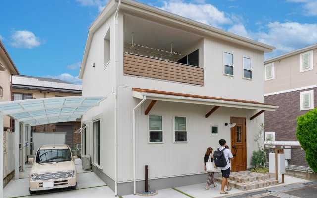 【施工事例：外観】白と木を融合したナチュラルで可愛らしい外観デザイン。玄関ポーチのタイルや庇で、カントリー調を感じられるコーディネートです。
