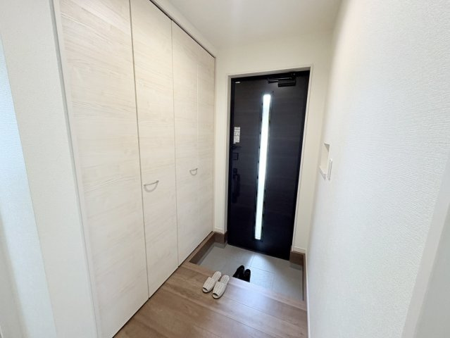 収納力のあるシューズボックスを備えた玄関。家族分の靴をしっかり収納でき、すっきりとした空間を保てます。縦長の採光付き玄関ドアにより明るさも確保。来客時の印象も良好です。毎日の出入りも快適に行えます。