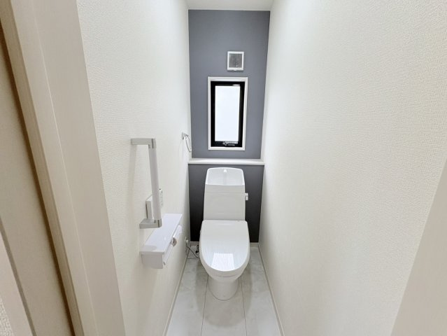アクセントクロスを採用したおしゃれなトイレ空間。窓付きで自然換気が可能なため清潔に保ちやすい設計です。温水洗浄便座付きで快適に使用できます。手洗い付きタンクで使い勝手も良好です。機能性を備えた水回り。