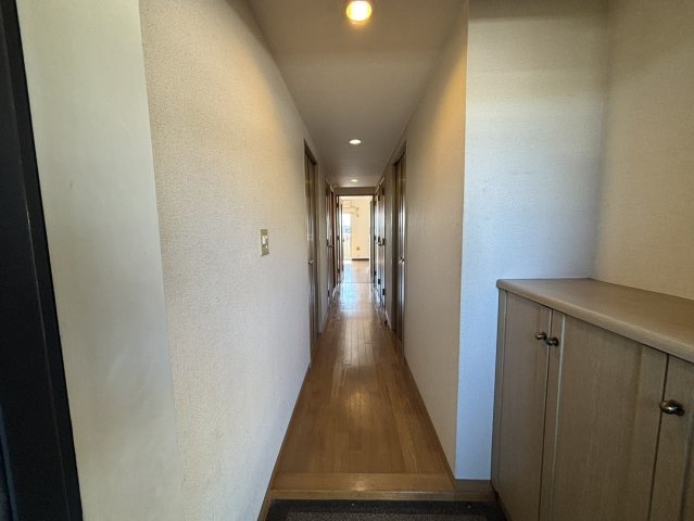 住まいの中心へとつながる落ち着いた雰囲気の廊下。木目調のフローリングが温かみを感じさせ、各部屋への動線もスムーズです。照明が明るく、シンプルで整っているため、来客時にも清潔感のある印象を与えます。