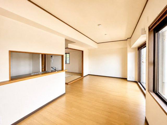 リビングダイニングは約13帖の広さがあり、家具配置がしやすい整形空間です。バルコニーに面した窓から自然光が入り、明るく開放感があります。キッチンは対面式で、リビングの様子を見ながら家事ができます。