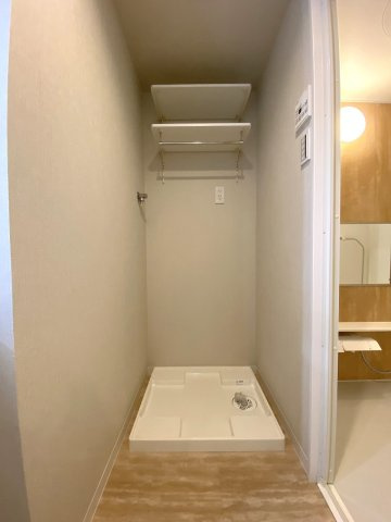 洗濯機置場です。上部や周辺に十分なスペースが確保されており、洗剤や洗濯小物を整理して配置できます。洗面室や浴室との動線もスムーズで、日々の洗濯作業を効率よく行える機能的な配置です。