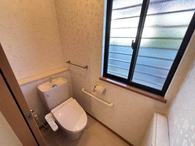 温水洗浄便座付きのトイレは窓があり明るく清潔感のある空間です。自然換気ができる為ニオイがこもりにくく日常的に快適に利用できるのが魅力。手すりも設置されており子供や年配の方も安心して使えるトイレです。