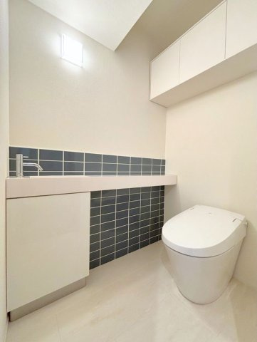 手洗いカウンターとタイルが空間のアクセントになっている落ち着いた印象のトイレ空間です。