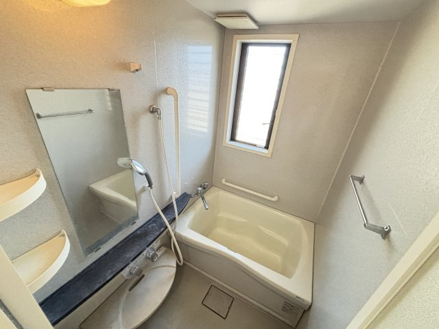 窓付きで明るく換気しやすい浴室はコンパクトながら使い勝手の良いレイアウト。湯船は深めでしっかり浸かれるサイズ感があり疲れを癒すバスタイムを提供します。手すりも設置されて子供からご年配の方まで安心です　