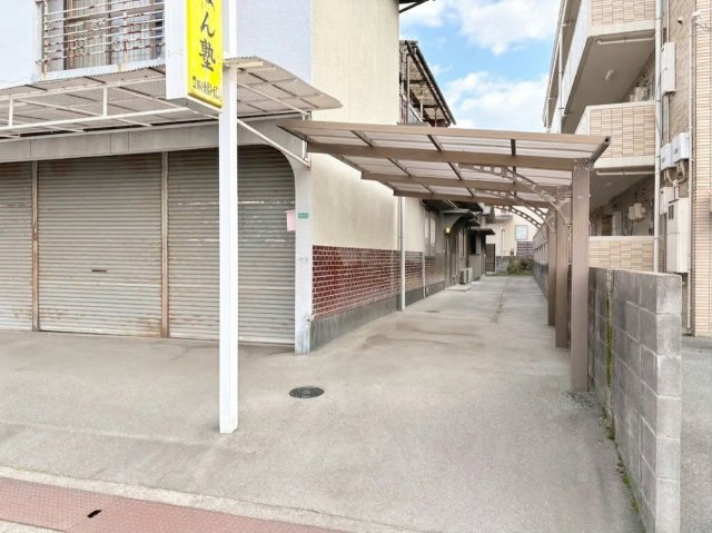 建物横には屋根付きの通路スペースがあり、雨の日でも濡れにくく移動できる点が魅力。カーポートが設置されているため、車の乗り降りや荷物の出し入れもしやすい環境。来客時や搬入などにも便利に活用できる実用的。