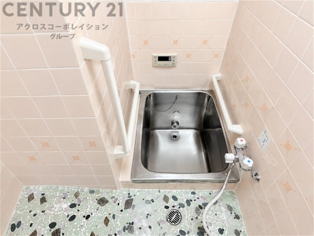 ステンレス製の浴槽を備えた、どこか懐かしさを感じる浴室。手すりも設置されており、毎日の入浴をサポート。コンパクトながら使い勝手に配慮された、落ち着きのあるバススペースです。