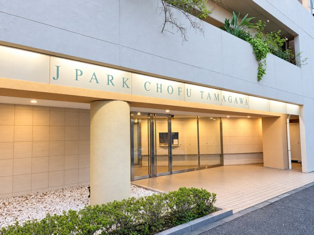 『J　PARK　CHOFU　TAMAGAWA』の館銘板を配したエントランス。落ち着いた印象の共用空間です。