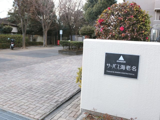 植栽に彩られた落ち着きのあるエントランス。マンション名を配した館銘板が迎える、管理の行き届いた印象の共用部です。