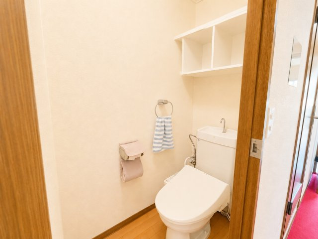 落ち着いた雰囲気のトイレ空間です。清潔感のある内装で、毎日気持ちよく利用できます。圧迫感を感じにくい配置となっており、快適に使用できる空間です。壁面には収納スペースもあり、トイレ用品を整理できます。