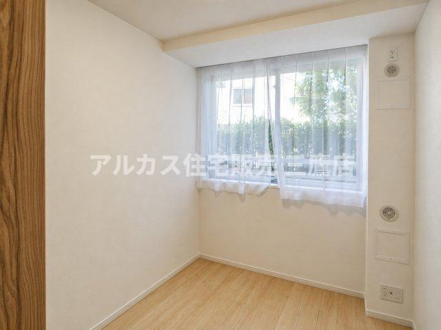 温もりある木目調のフローリングとシンプルな壁面が調和した、落ち着きのある居室。