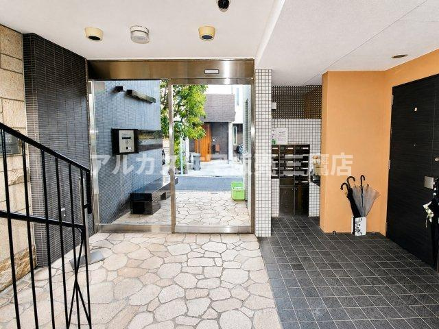 石畳風の床と落ち着いたトーンの壁面が調和する、開放感あふれるエントランスホール。