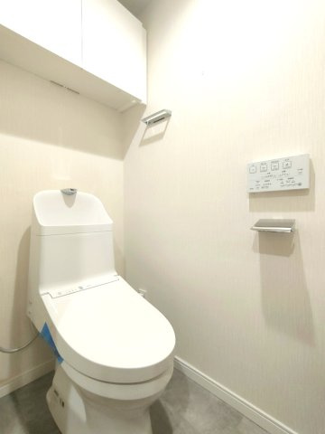 【トイレ】　上部に吊戸棚を備えた、清潔感のある明るい空間です。トイレは温水洗浄便座付です。