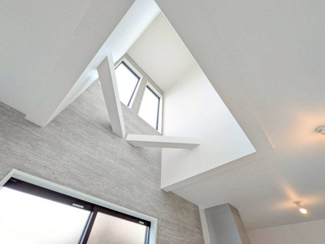 リビングの大きな吹き抜けから降り注ぐ明るい日差しが、空間全体を開放感で満たし、自然と家族が集まる暖かな空間を創り出します。高い天井と光に包まれたこの場所が、家族の笑顔を育む住まいの中心に！（施工例）