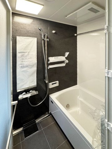 黒のパネルが落ち着いた空間を演出する、清潔感あふれる浴室。浴室乾燥機も完備し、雨の日の洗濯も安心です。