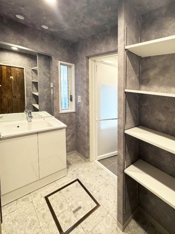 グレーの石目調クロスにワイドミラーを配した、ホテルクオリティの洗面空間。