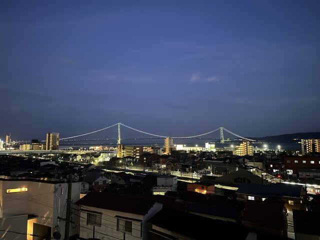【屋上バルコニーからの眺望】　夜はライトアップされた「明石海峡大橋」を望むことができます。時間帯によって変化する眺望をご堪能いただけます。在宅ワークや家事の合間に外気に触れてリフレッシュできそうです。