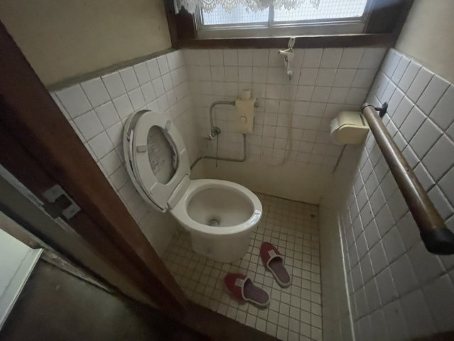 窓を備えたトイレで、自然光を取り込みながら換気もしやすい空間。壁や床にはタイルが使用され、昔ながらの雰囲気が残っています。設備や内装を交換することで、清潔感のある使いやすい空間へ一新することもできます