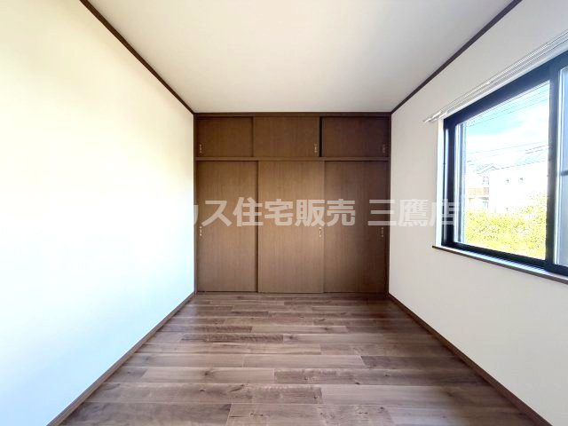 壁面一杯に大きな収納を備えた、自然光が心地よく差し込む落ち着いた洋室。