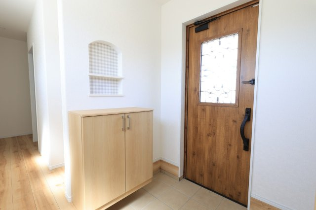 木目のドアとタイルの組み合わせが上品な印象を与える玄関。　ニッチのワンポイントが、住まいにさりげないデザイン性を添えています。