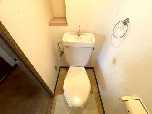 シンプルで清潔感のあるトイレスペース。背面には小物を置ける棚があり、芳香剤や装飾なども楽しめます。手洗い一体型でスペースを有効活用しつつ、節水効果も期待できます。
