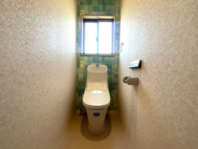 窓付きで換気がしやすく、明るさも感じられる清潔感のあるトイレ空間。アクセントクロスが空間のデザイン性を高め、毎日使う場所にもおしゃれな雰囲気を演出しています。温水洗浄便座付きで機能性にも配慮。