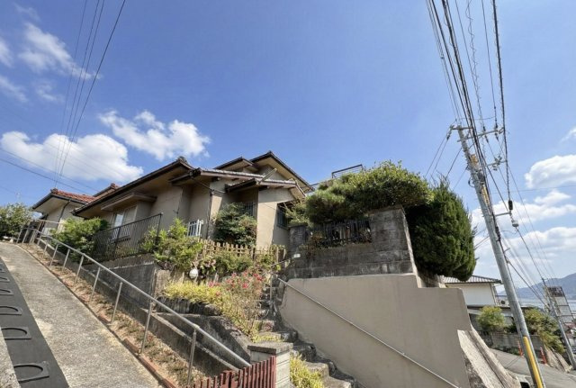高台に位置した外観は、通風・採光に恵まれた心地よい住環境です。外構は段差を活かした造りで、植栽が程よく配置され落ち着いた印象です。周囲の視線を気にしにくく、静かに暮らせる住まいです。