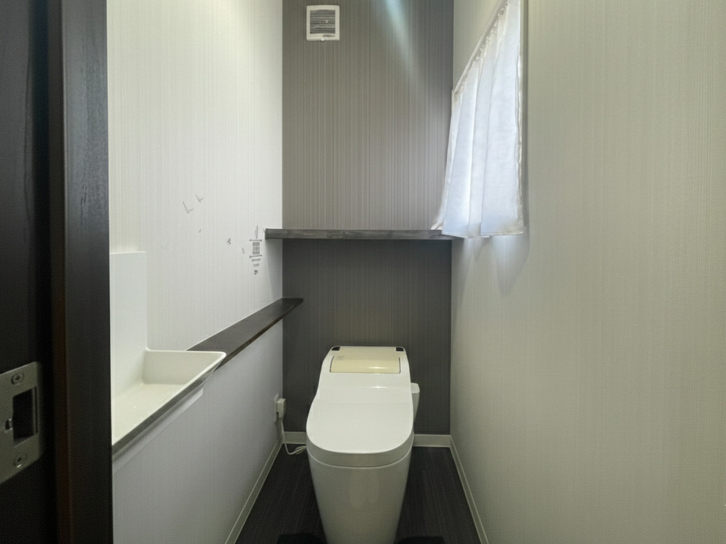 スタイリッシュなタンクレスタイプのトイレ。すっきりとしたフォルムで空間を広く感じさせます。カウンター付きで小物やインテリアも配置可能。窓から自然光が入り、明るく換気もしやすい環境です。