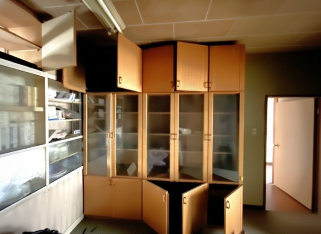 壁一面に設置された大型収納棚が特徴の空間で、本や食器、日用品などをたっぷり整理できます。現状は年季を感じますが、扉の交換や塗装、照明の工夫を加えることで、清潔感ある収納スペースに生まれ変わります。